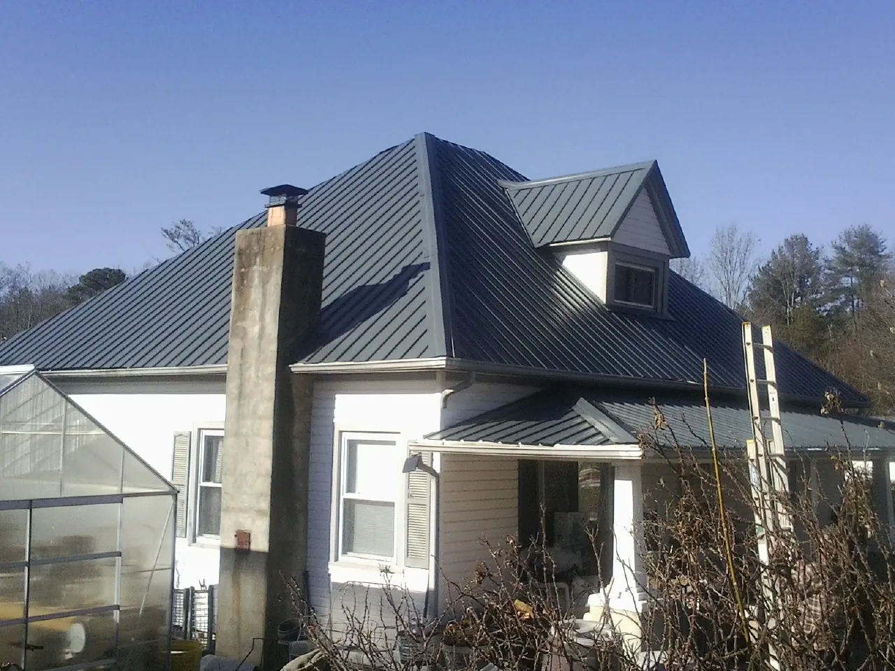 Dark blue standing seam metal roof on a white farmhouse with dormer — Slate & Tile Roof Repair by Roofing Brothers in Othello