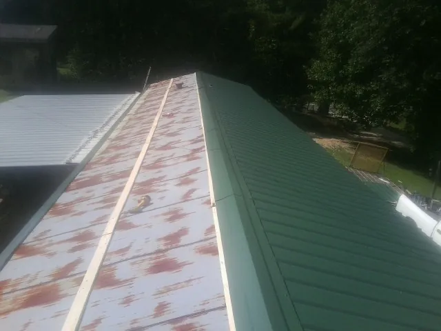 Old rusted panels beside newly installed green metal roofing — Wind Damage Roof Repair by Roofing Brothers in Othello