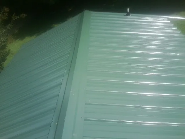 New green metal panels meeting at the ridge of a roof — Flat Roof Repair work by our crew in Othello