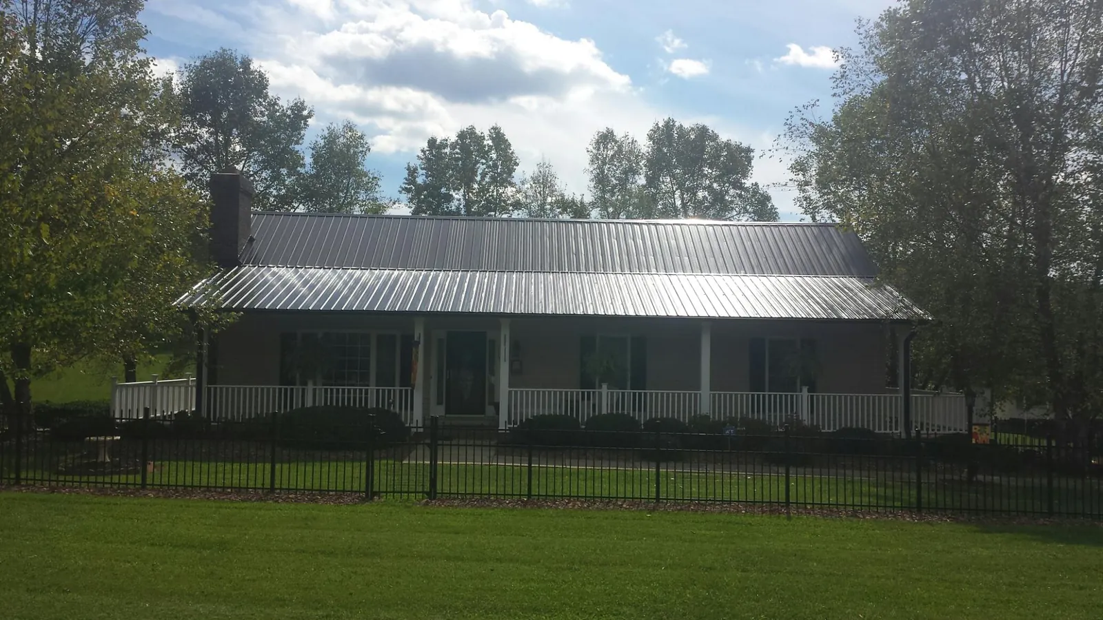 Gray metal roof on a brick ranch with a full width front porch — Gutter Guard Installation work by our crew in Othello